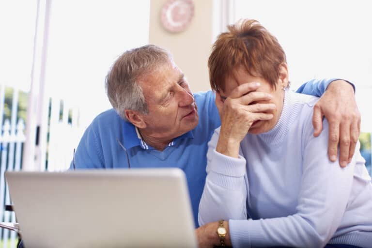 An older man and woman examining technology.