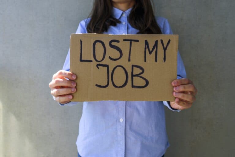 Woman in blue shirt with cardboard sign LOST JOB